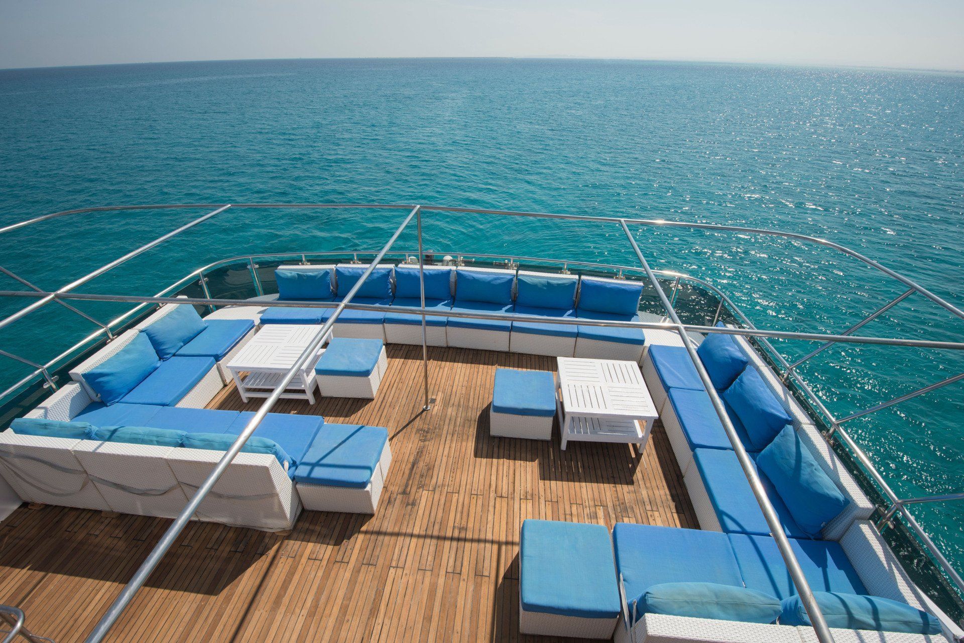 A boat with a lot of blue cushions on the deck is in the ocean.