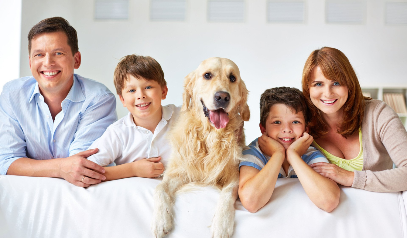 A family is sitting on a bed with a dog.