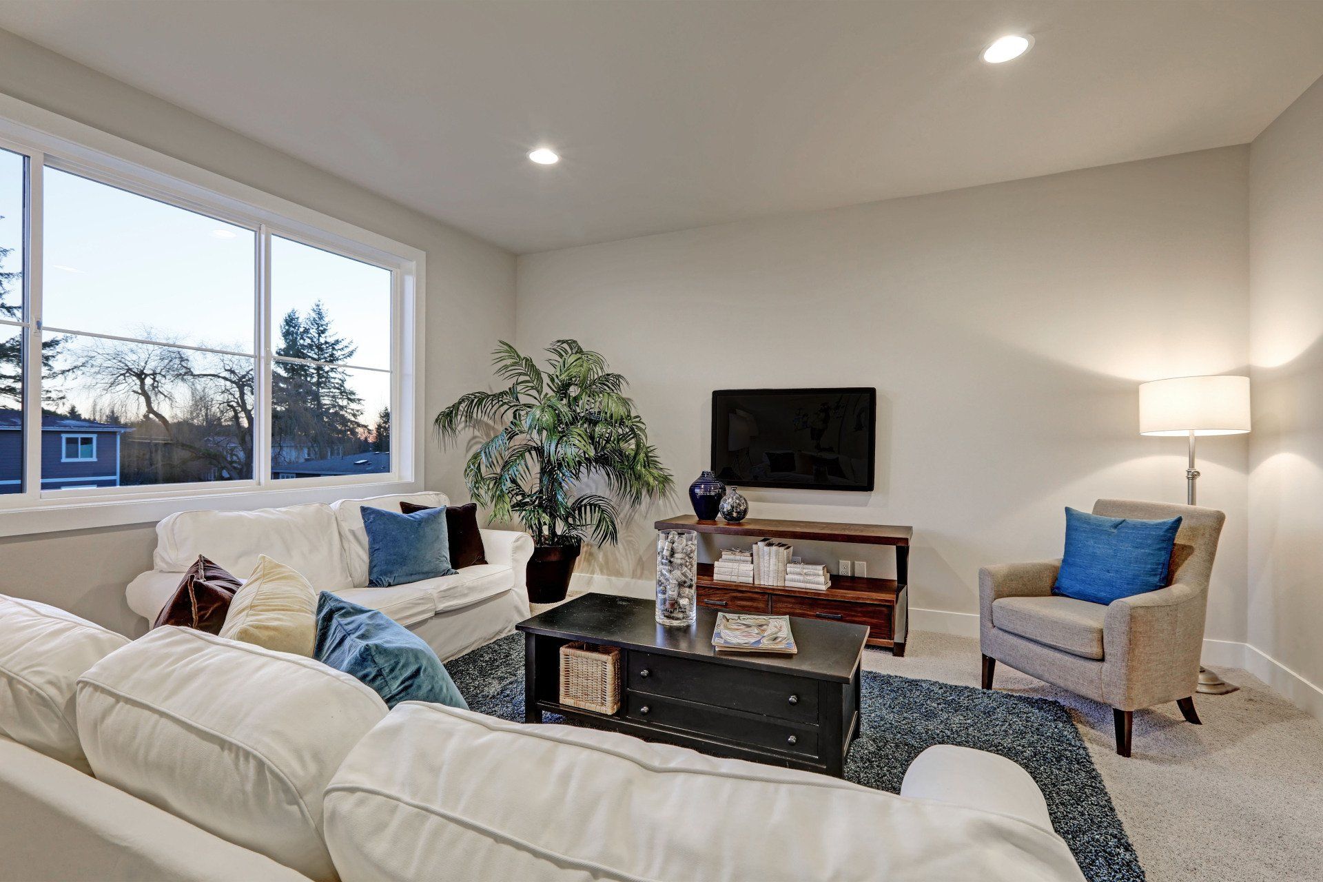 A living room with a couch , chairs , coffee table and television.