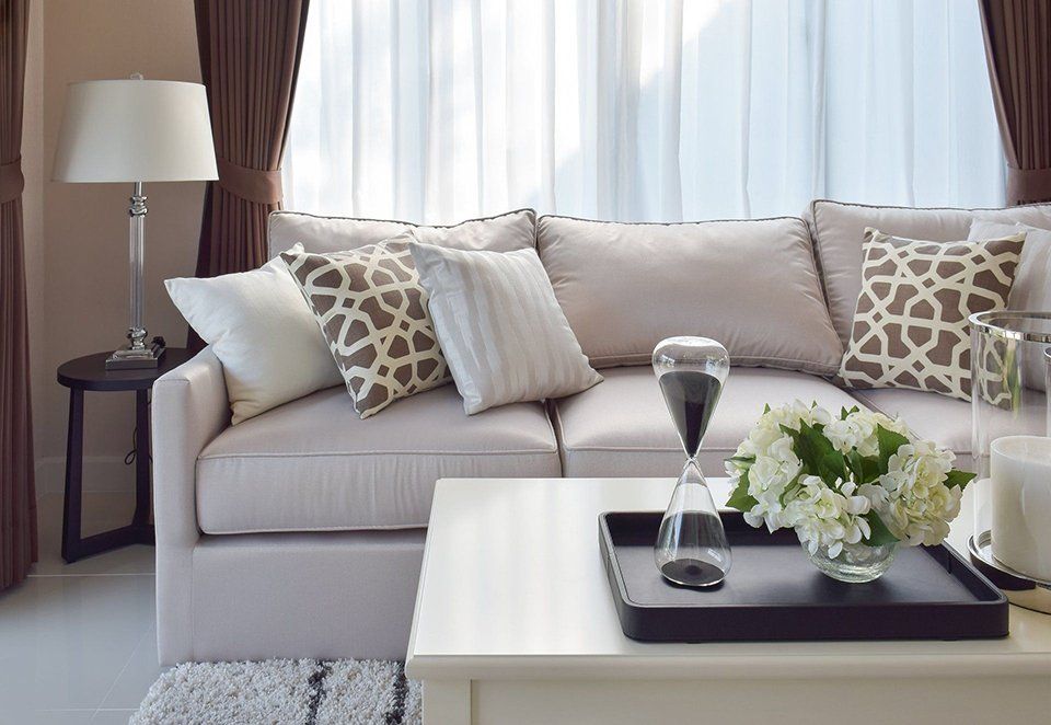 A living room with a couch , table , lamp and vase of flowers.