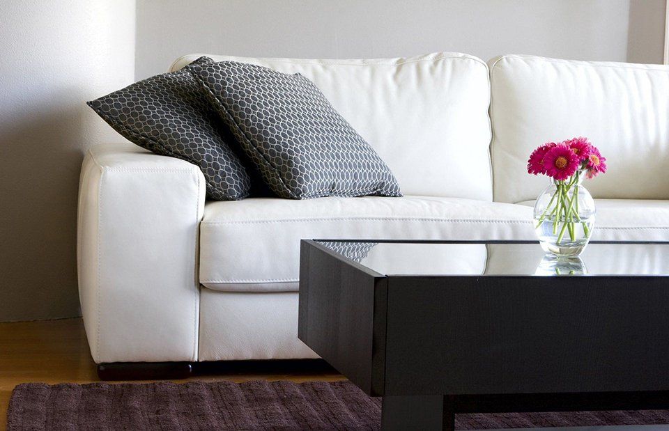 A living room with a white couch and a black coffee table
