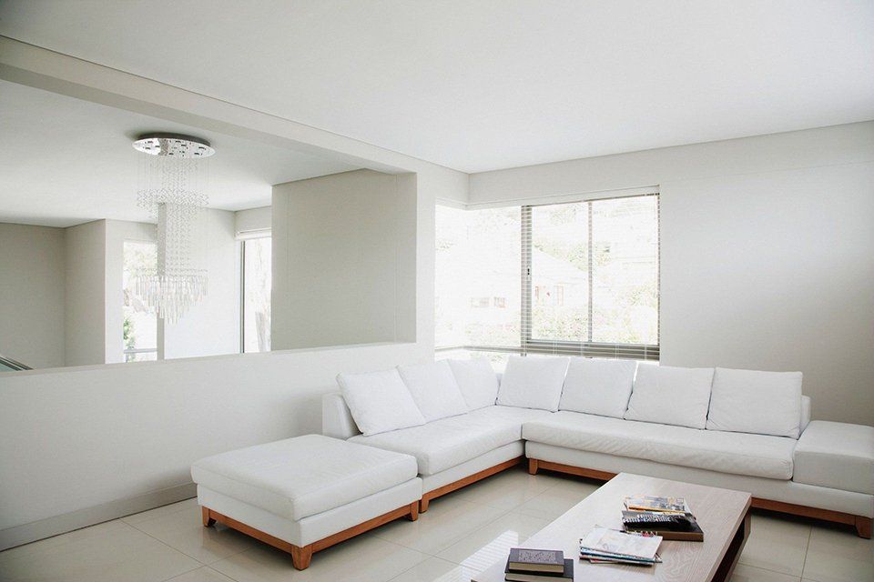 A living room with white furniture and a large mirror on the wall.