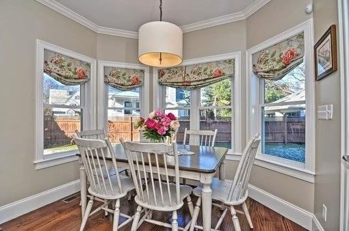 A dining room with a table and chairs and lots of windows.
