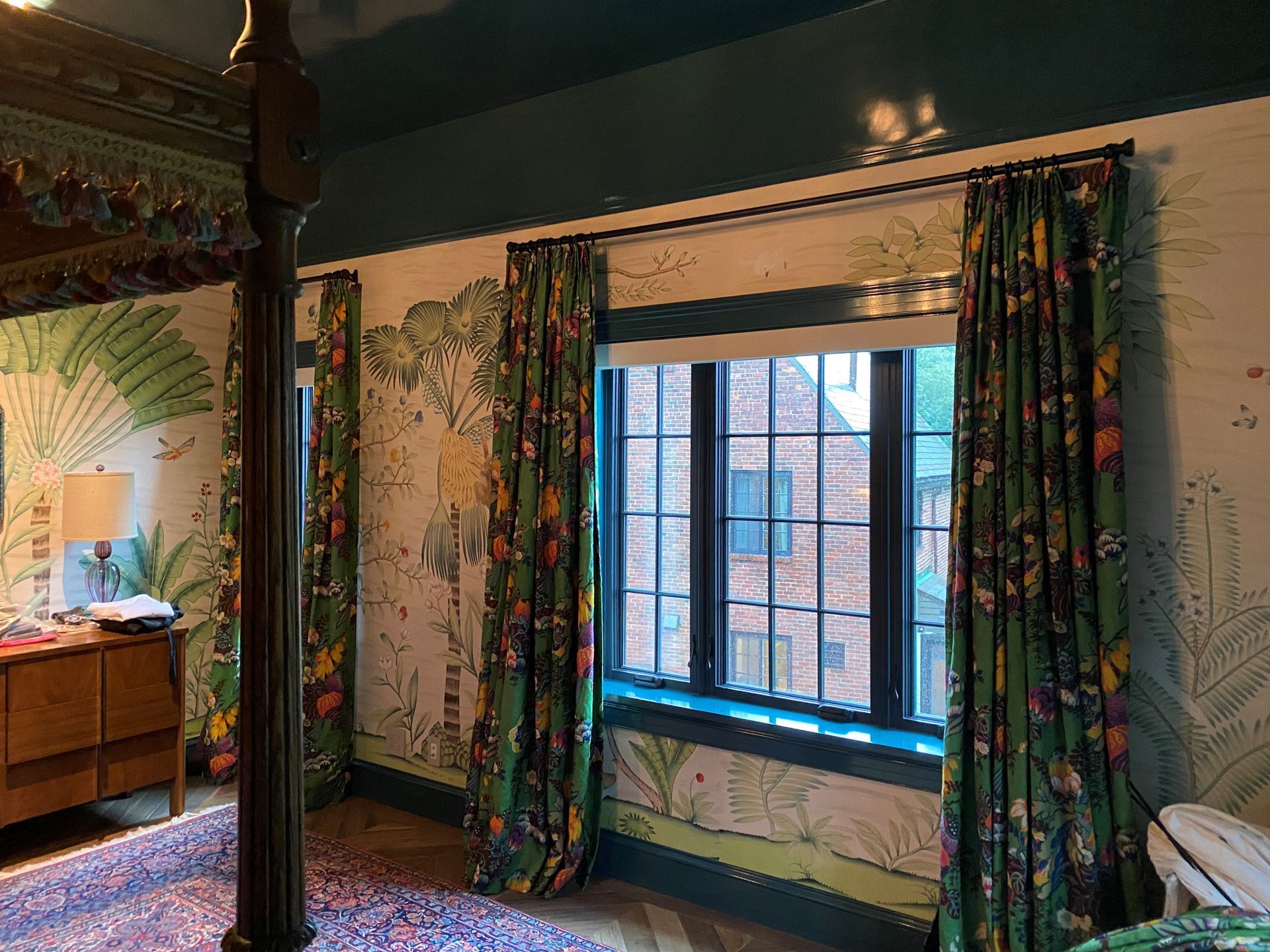 A bedroom with green curtains and a large window.