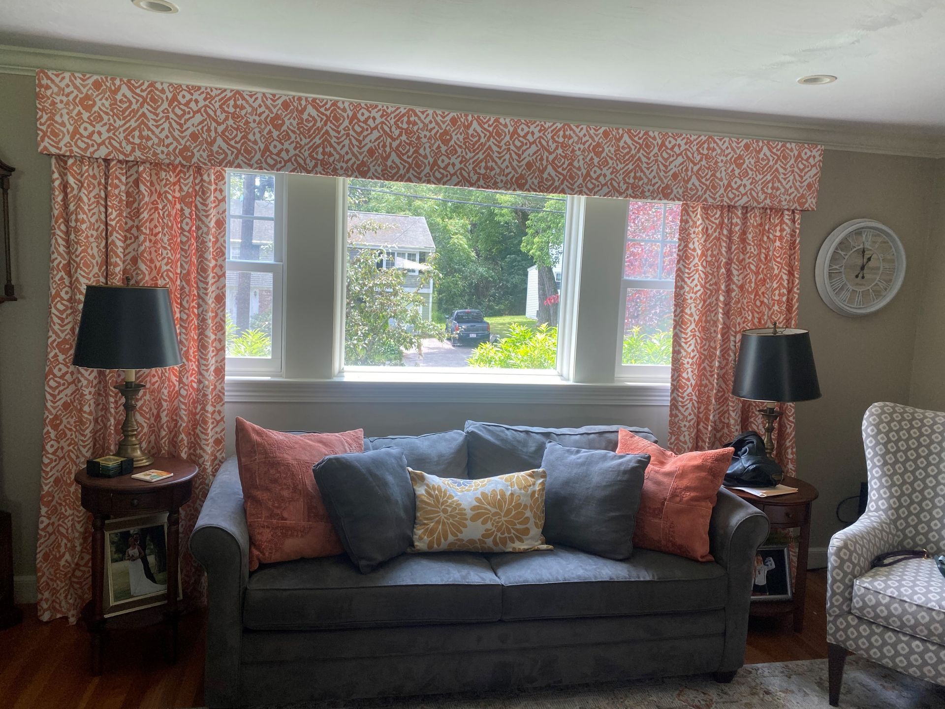 A living room with a couch , chair , lamps and a window.