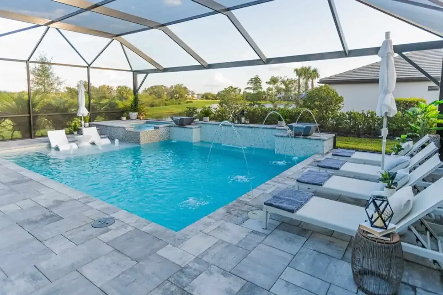 Lanai with a turquoise pool, lounge chairs, and patio seating under a screened enclosure