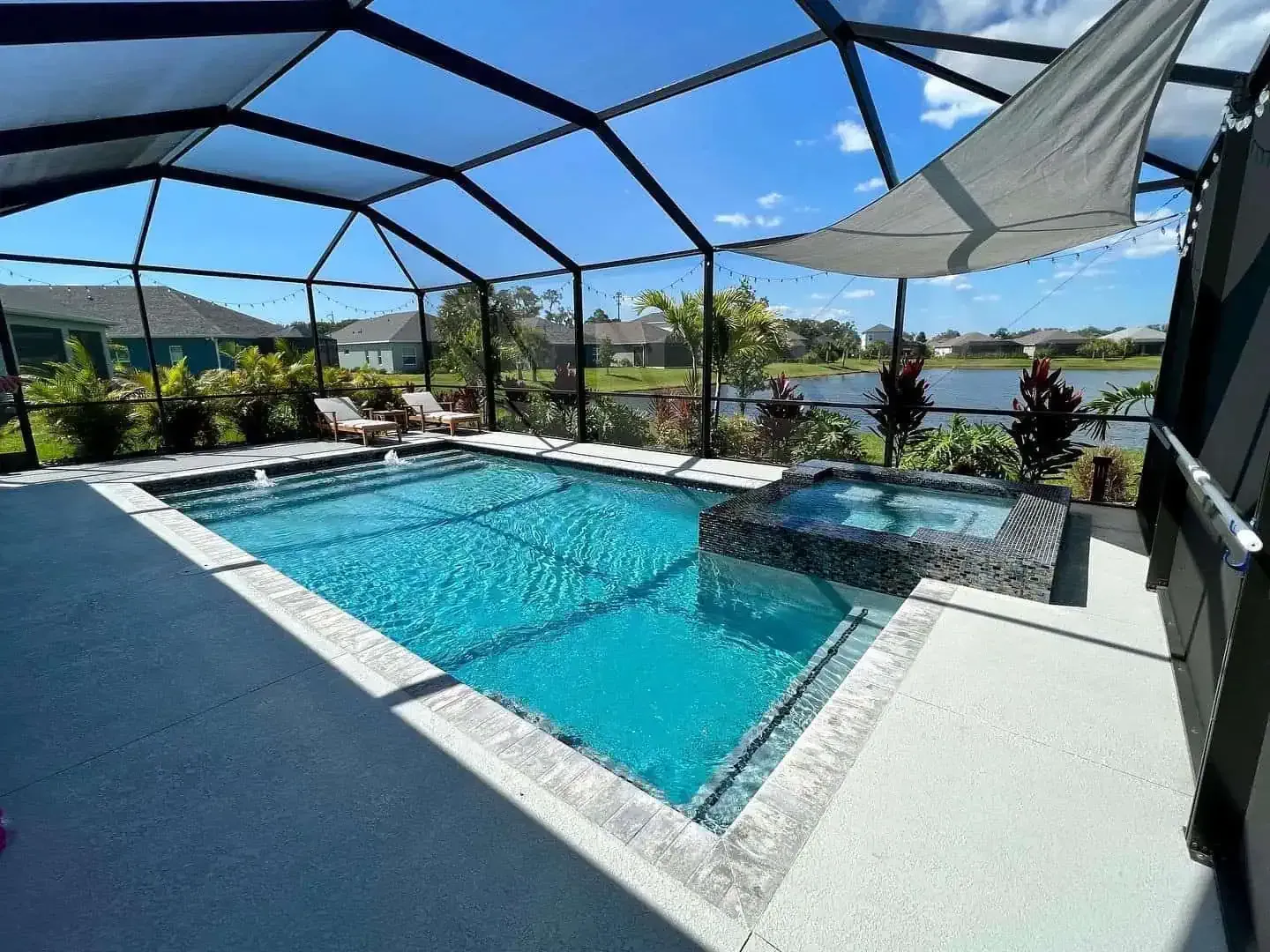 Screened backyard pool and spa with blue water, white deck, and mountain view under a black enclosure