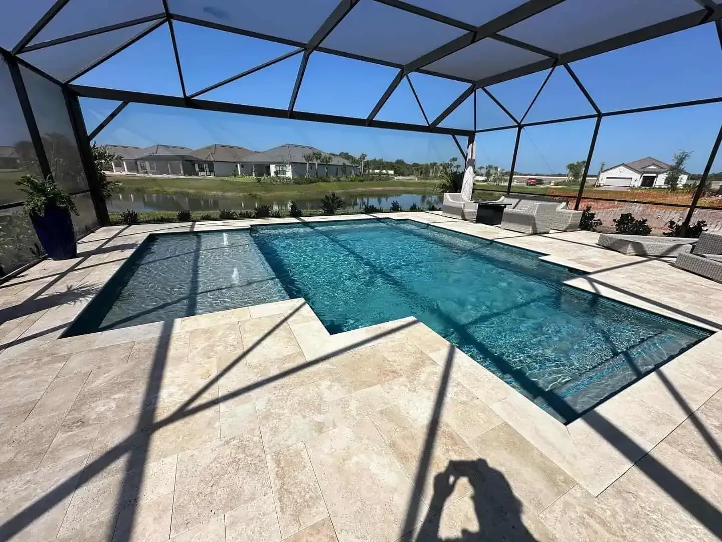 Screened backyard pool with blue water and patio under a black mesh enclosure, overlooking a golf course