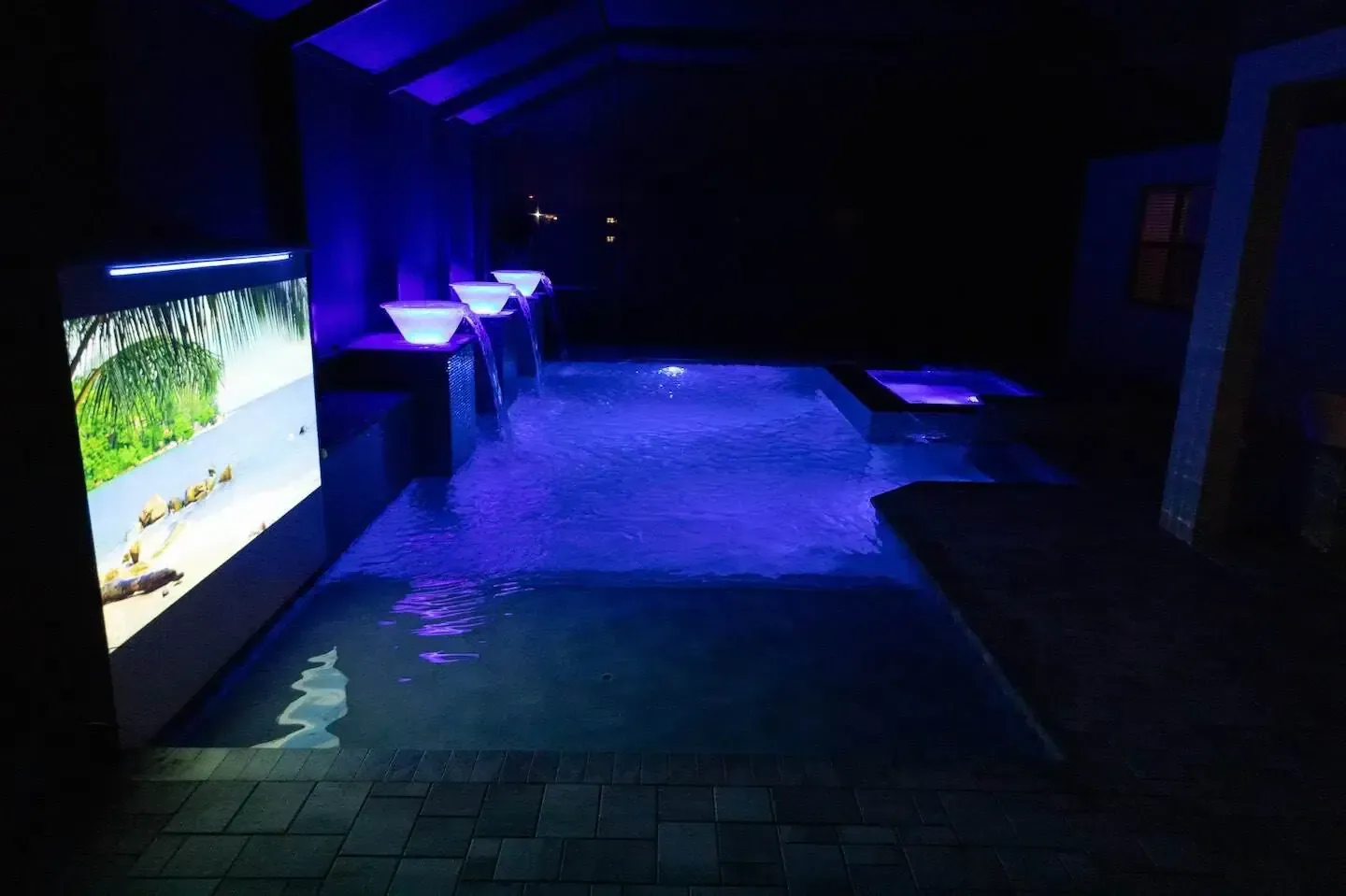 Dim blue-lit indoor walkway with glowing aquarium-like displays along the left side
