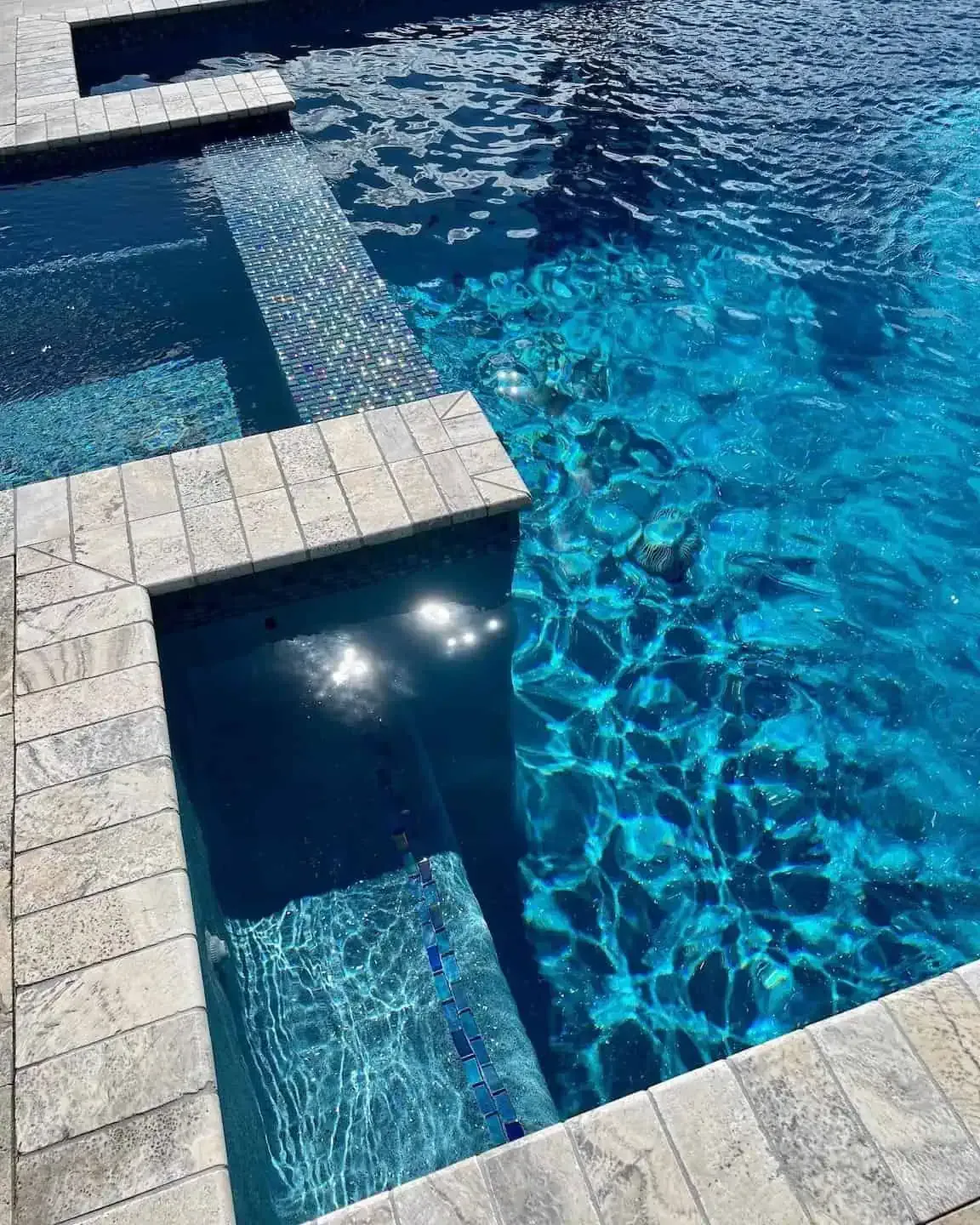 Modern blue swimming pool with tiled edges and clear water reflecting sunlight