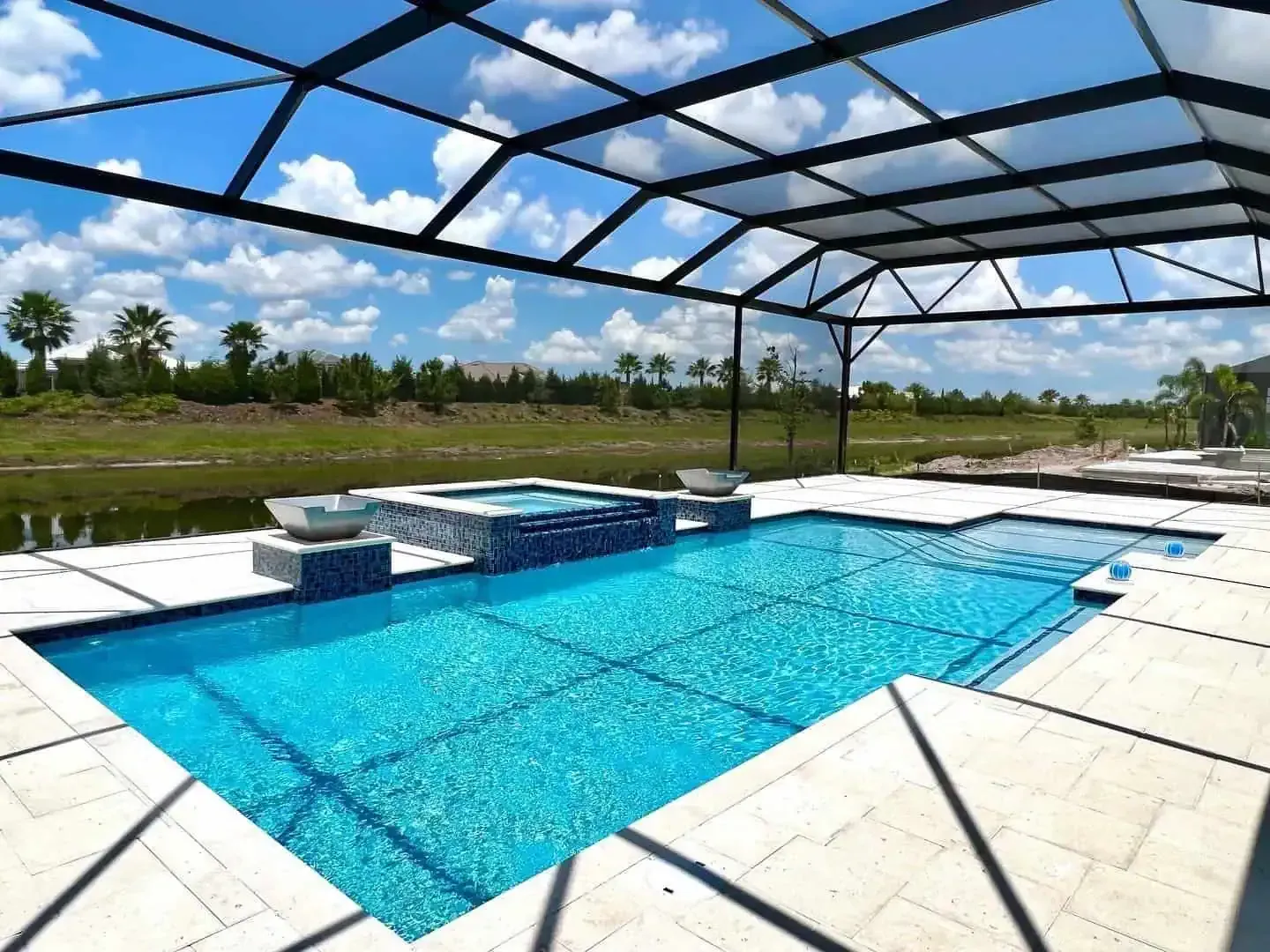 Blue backyard pool with a screened enclosure, white deck, and sunny sky view