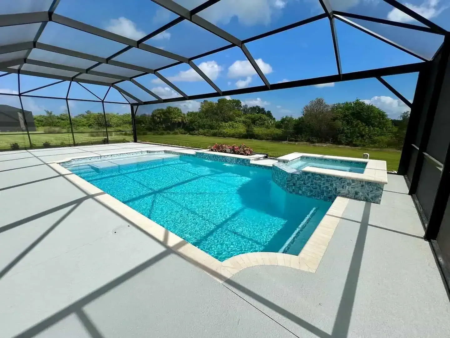 Screened-in backyard pool with blue water, white deck, and sunny sky beyond the enclosure