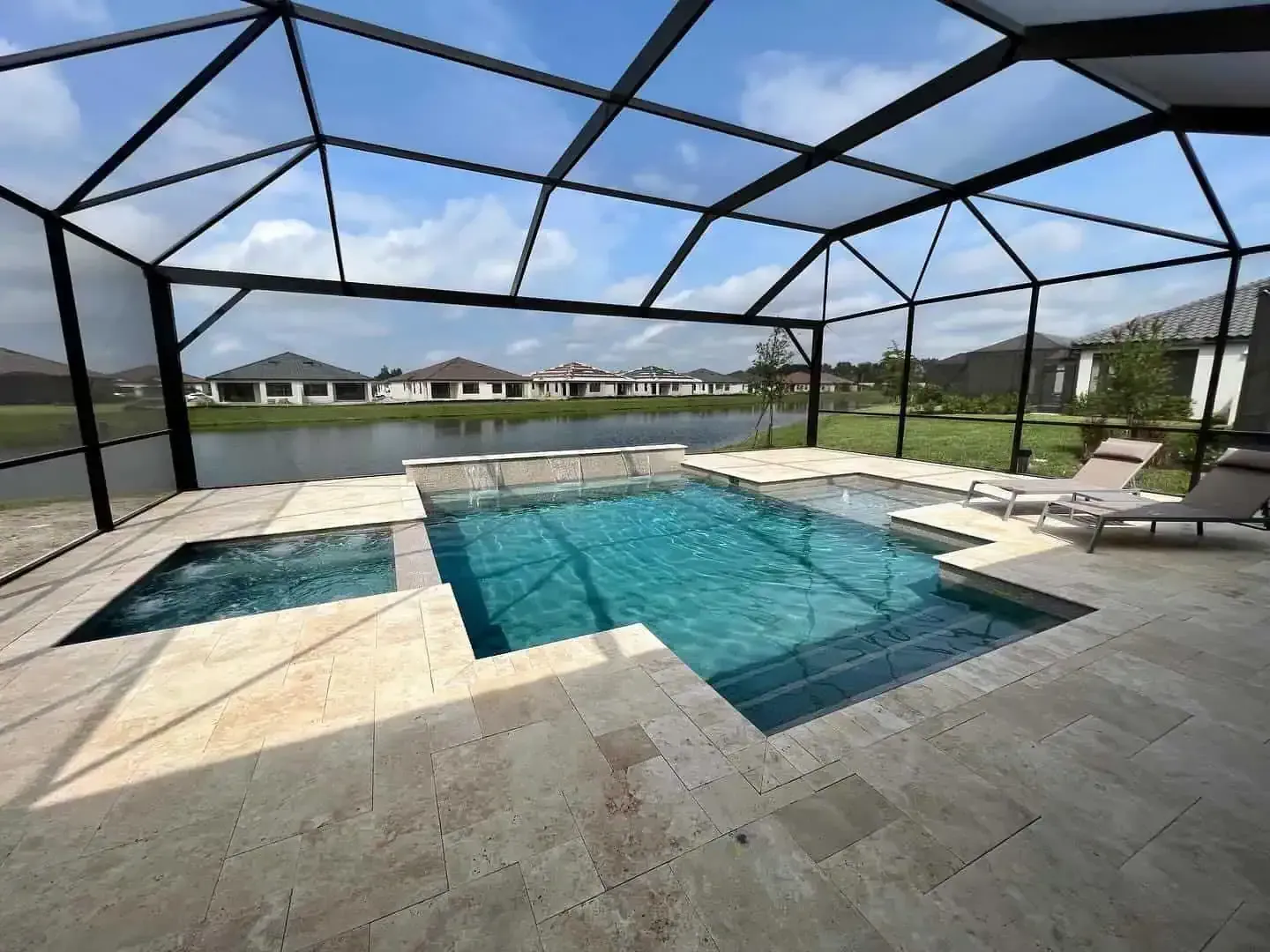 Screened backyard pool with stone patio, lounge chairs, and bright blue water under a clear sky