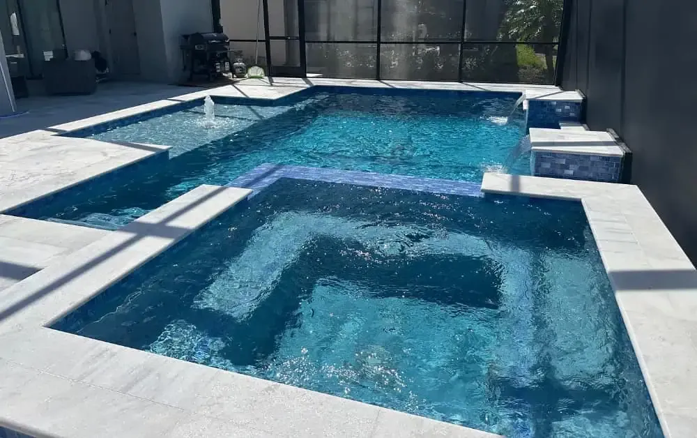 Modern backyard pool with a square spa inset and blue water, surrounded by a screened patio.