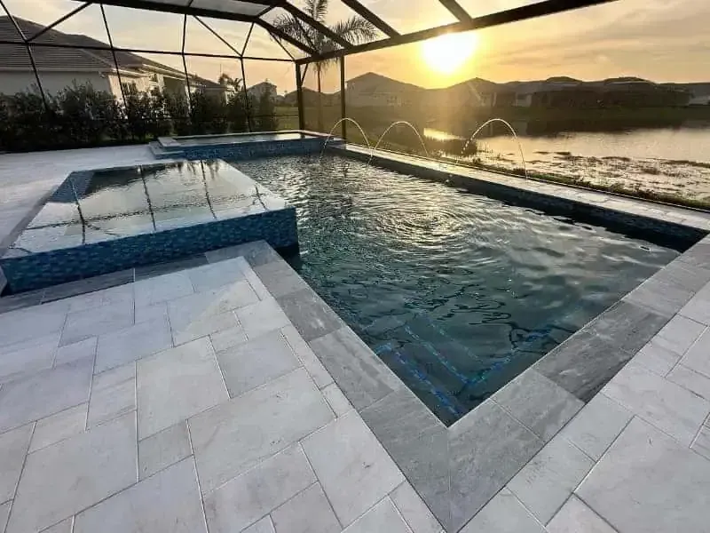 Infinity pool under a canopy at sunset overlooking water and hills