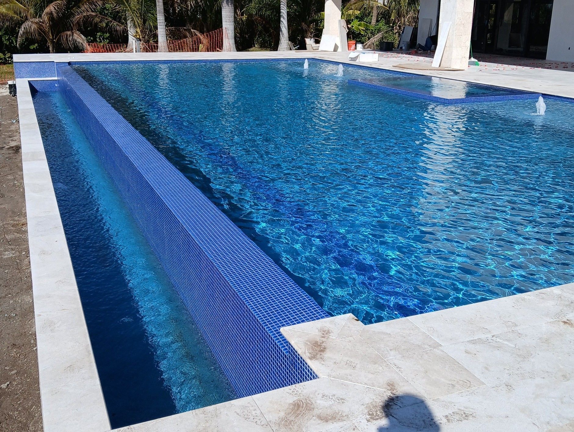 Outdoor swimming pool with blue tiled steps and clear blue water under a sunny patio area