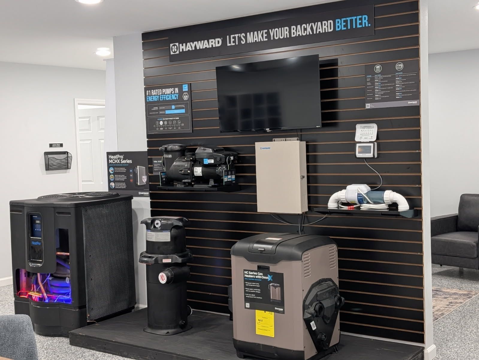 Electronics display wall with TVs, speakers, and gaming consoles in a retail store.
