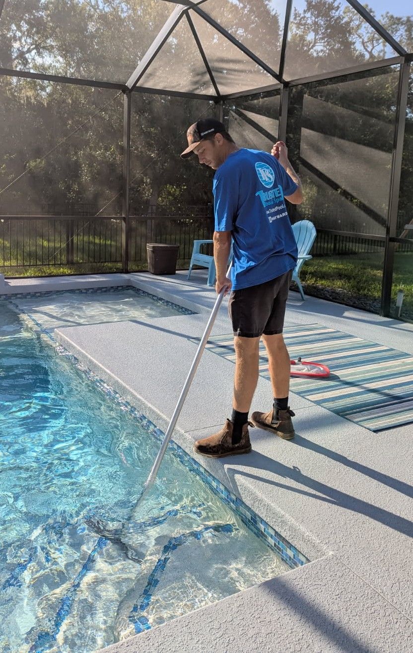 Man cleaning a screened pool with a long skimmer net beside blue water