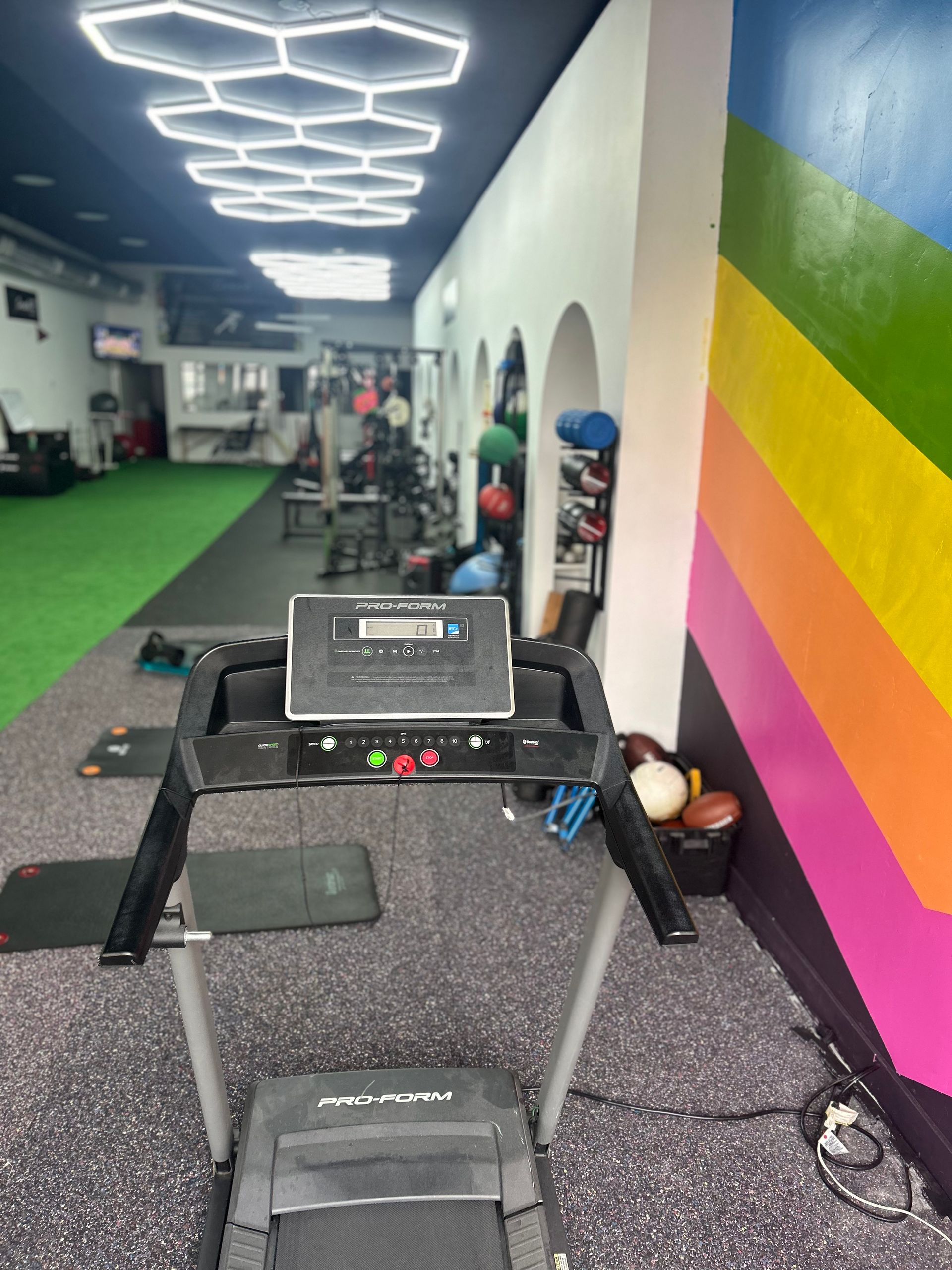 A treadmill in a gym with a rainbow wall