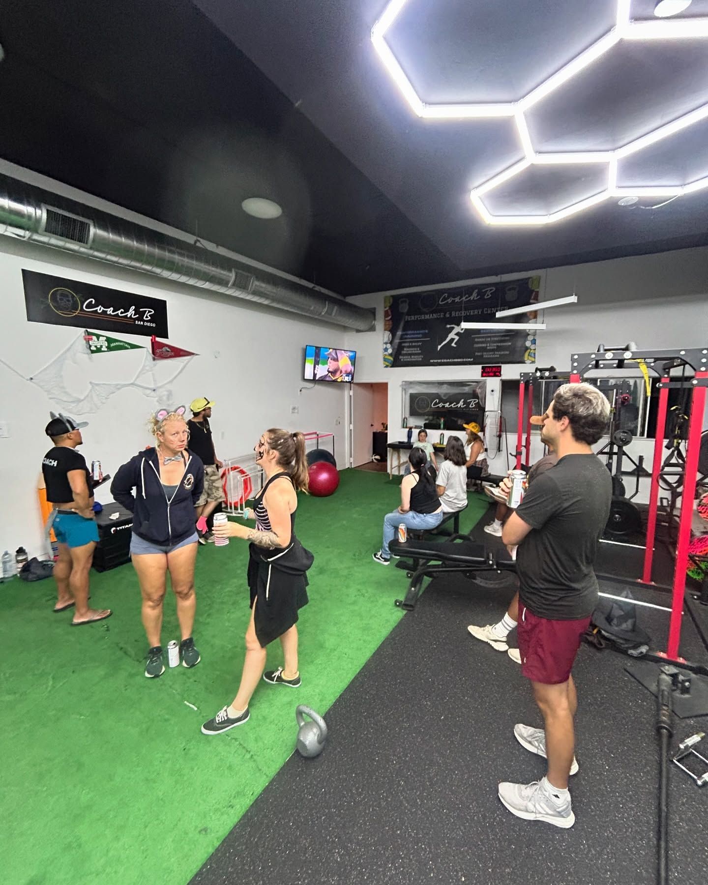 A group of people are standing in a gym talking to each other.