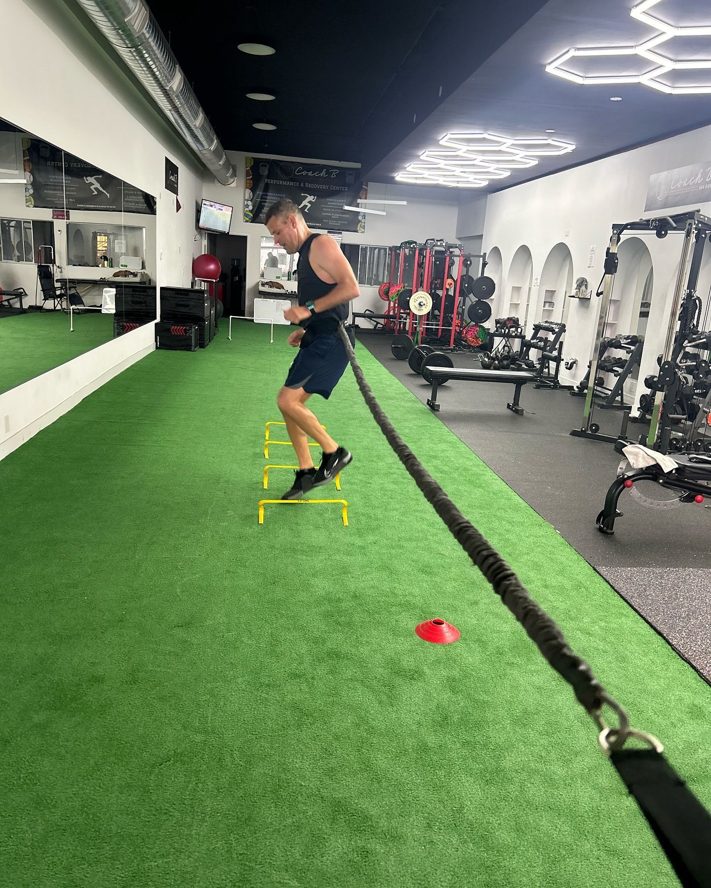 A man is jumping over a rope in a gym.
