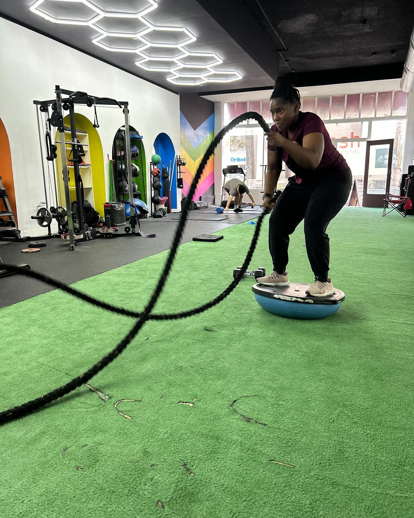 A woman is doing exercises with a rope in a gym.