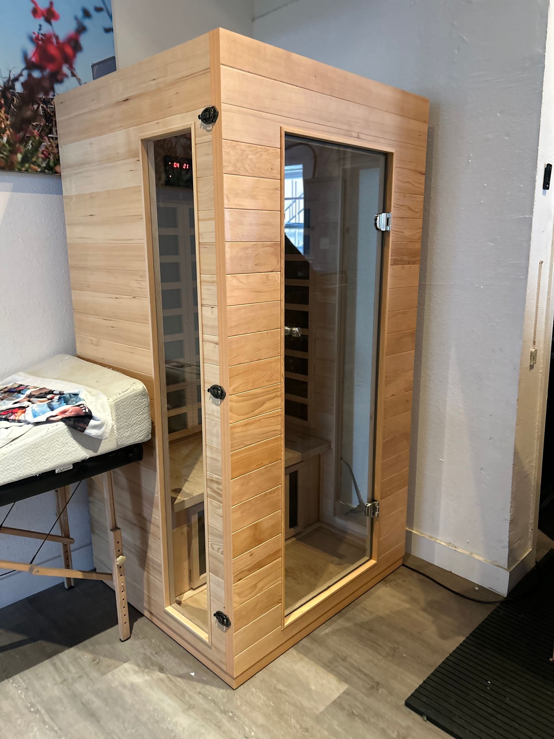 A wooden sauna is sitting in a room next to a table.