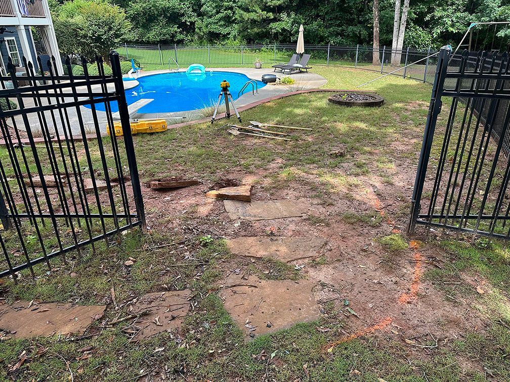 A backyard with a fence and a pool in the background.