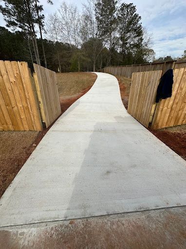 A concrete driveway leading to a wooden fence.