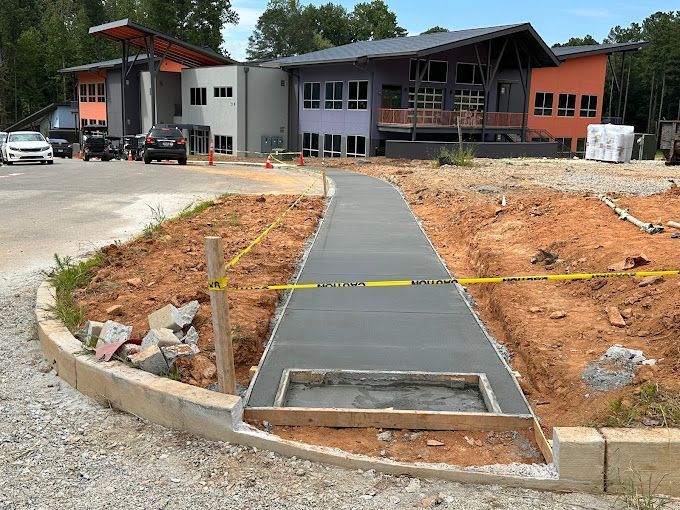 A concrete walkway is being built in front of a building under construction.