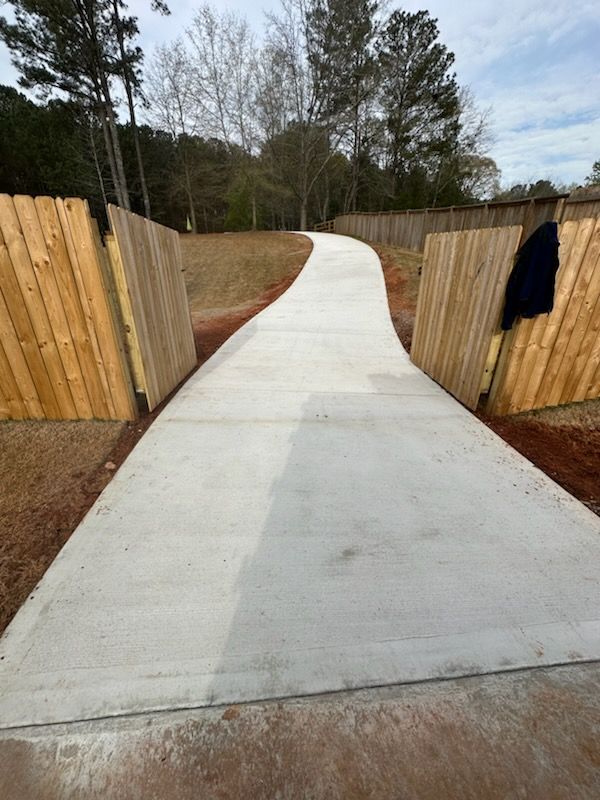 A concrete driveway with a wooden fence on both sides