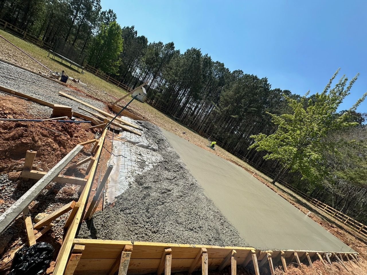 A concrete driveway is being built on a hill with trees in the background.