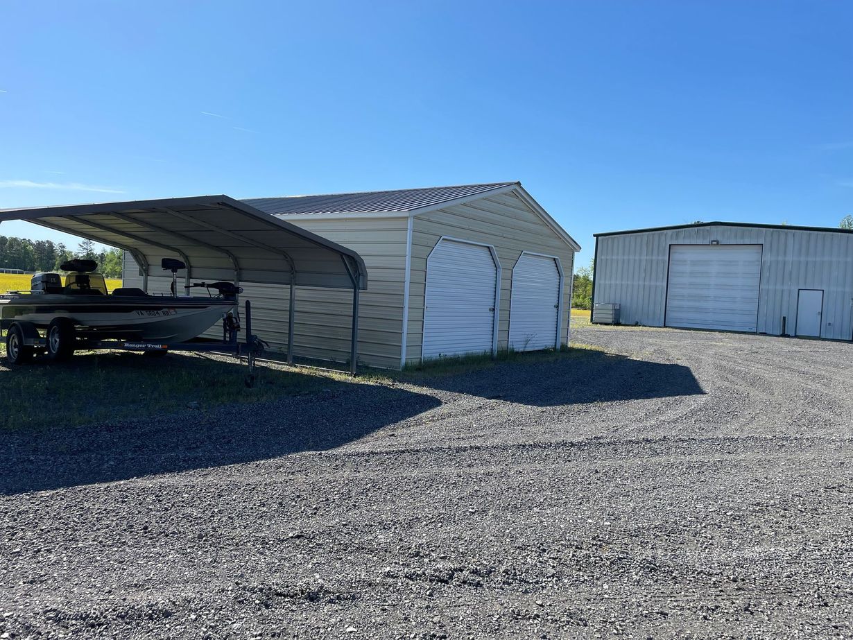 A row of closed, light green metal garage doors with white pillars under a clear blue sky.
