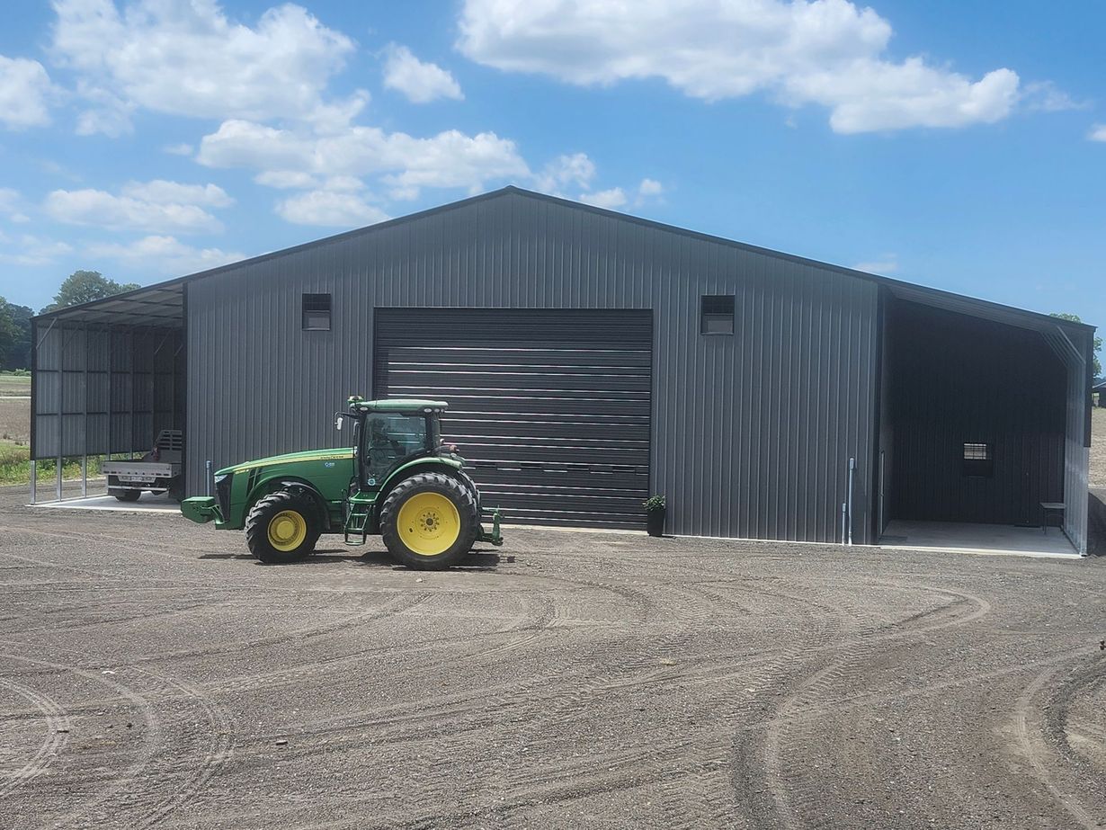 Two grey metal storage units or hangars with roll-up doors against a clear blue sky.