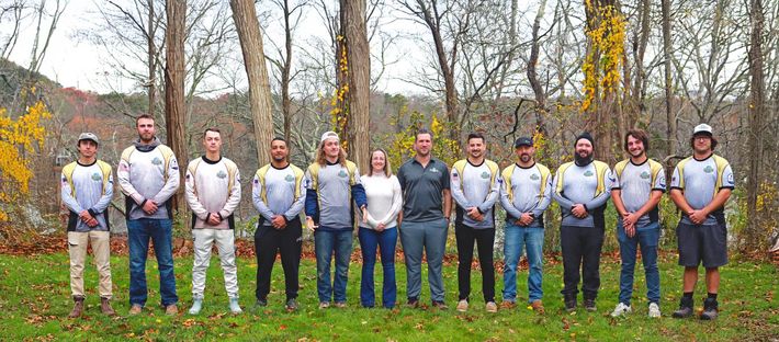 A group of people are posing for a picture in front of trees.