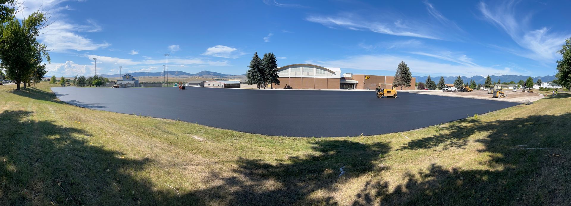 A freshly paved lot with a building in the background, a sunny day.