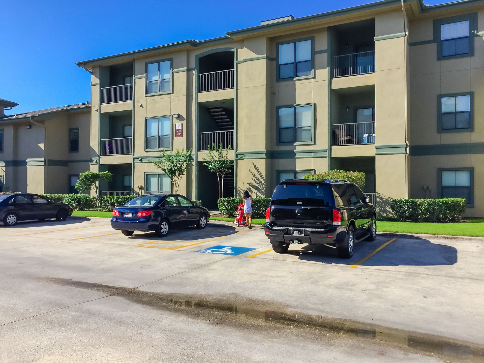 Several cars are parked in front of a large apartment building