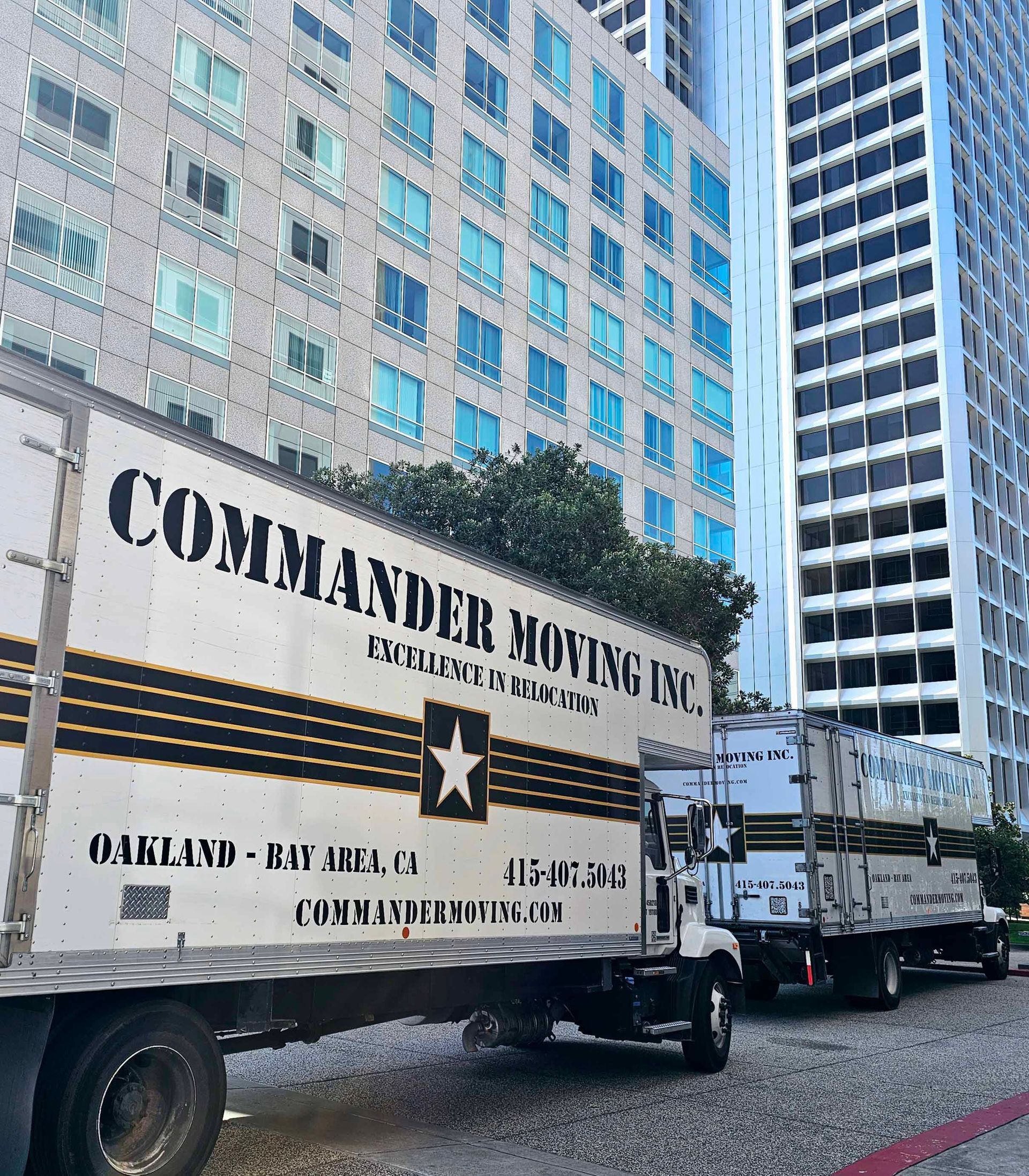 Moving trucks parked in front of tall buildings. 