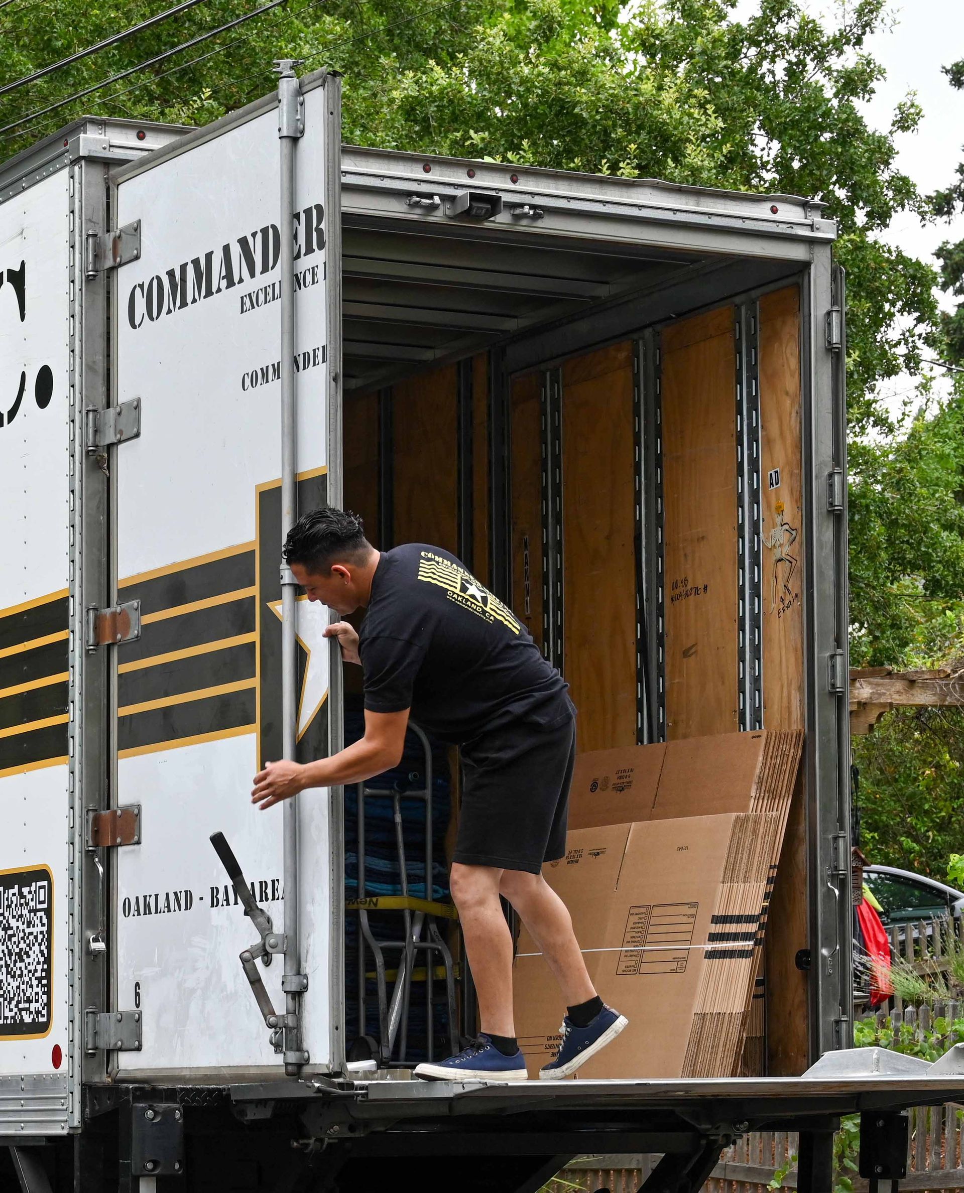 Man loading cardboard boxes into a moving truck with a yellow and black logo.