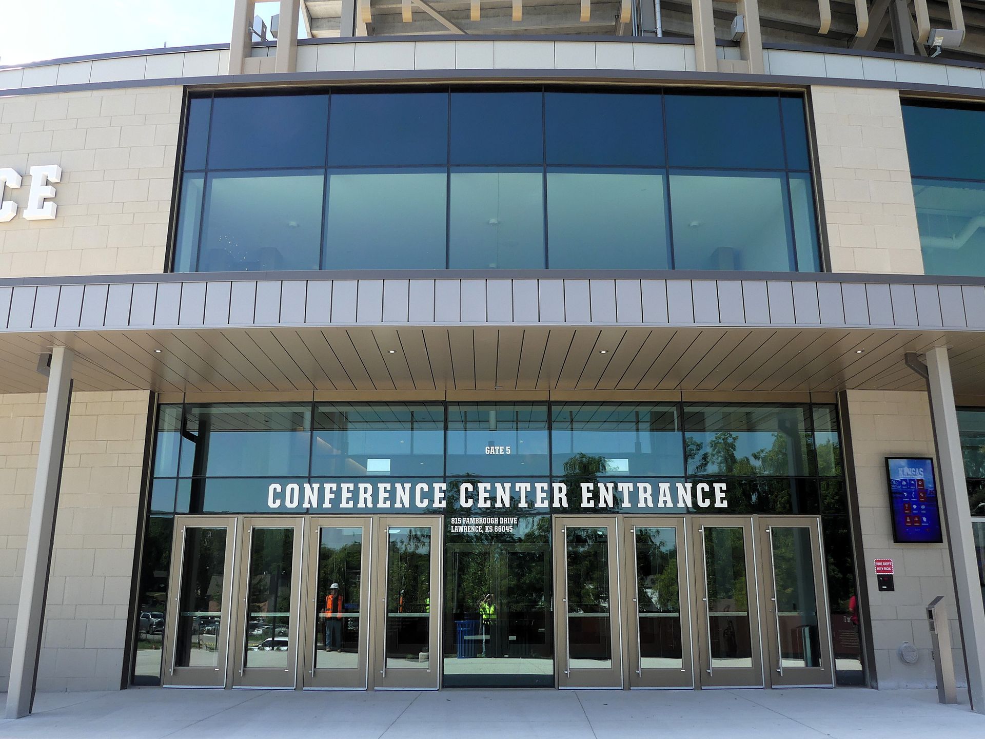 Conference center entrance with glass doors, signage, and light-colored brick facade.