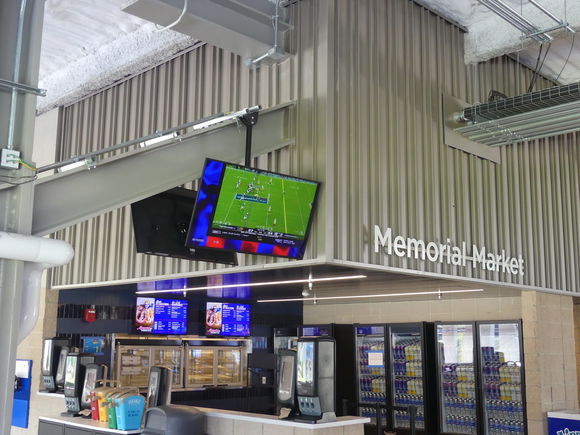 Memorial Market with TVs displaying sports, a counter, and refrigerators with products.