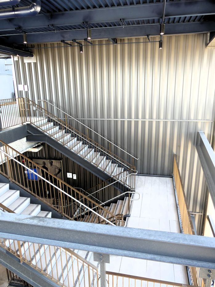 Staircase with metal railings and corrugated silver wall.