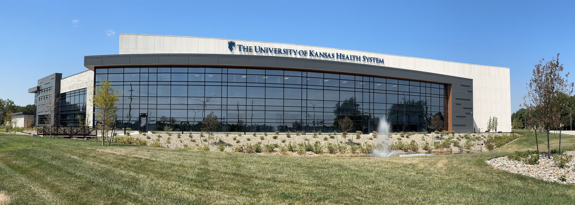 A large building with a lot of windows is sitting in the middle of a grassy field.