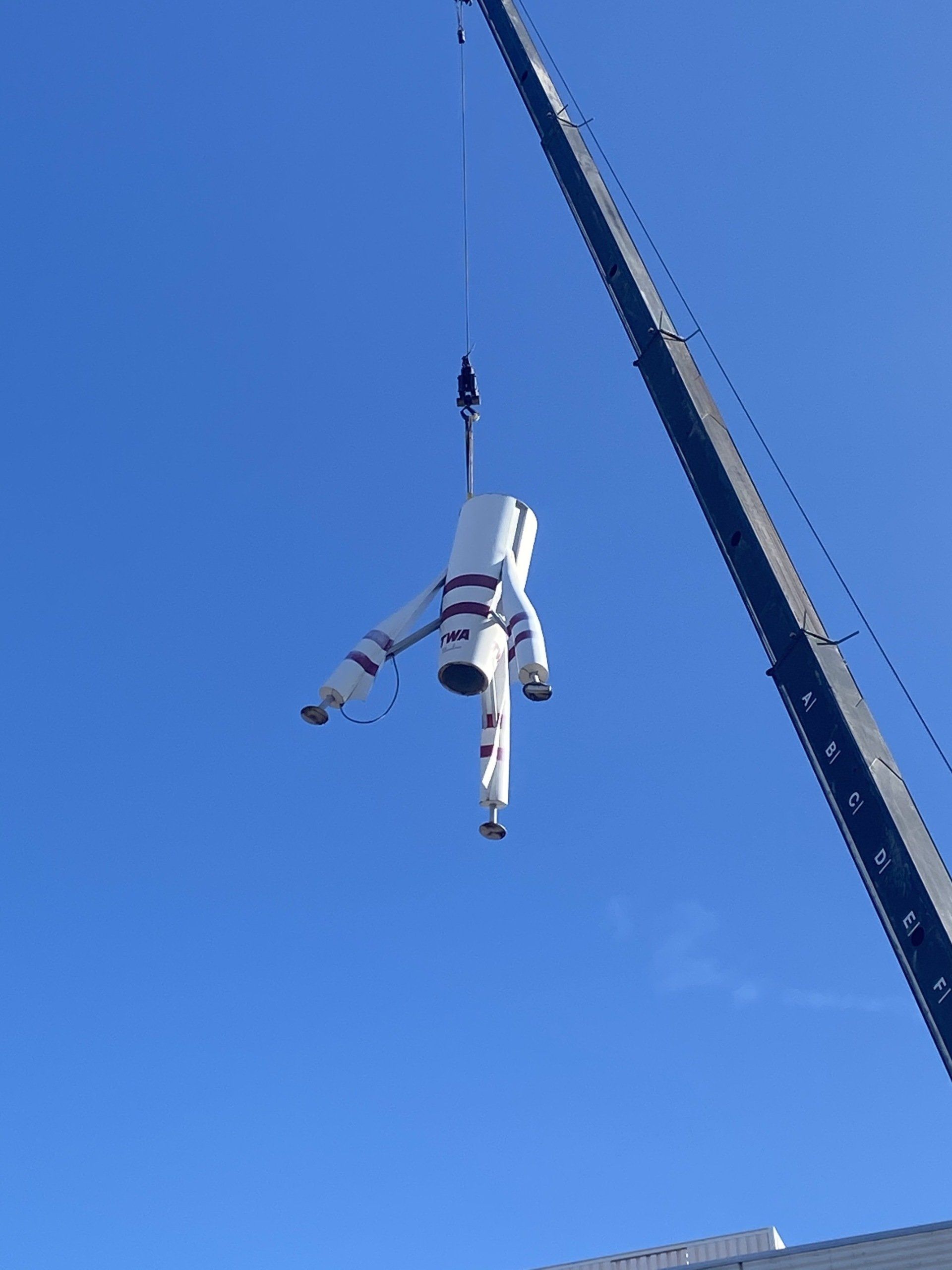 A statue of an astronaut is being lifted into the air by a crane