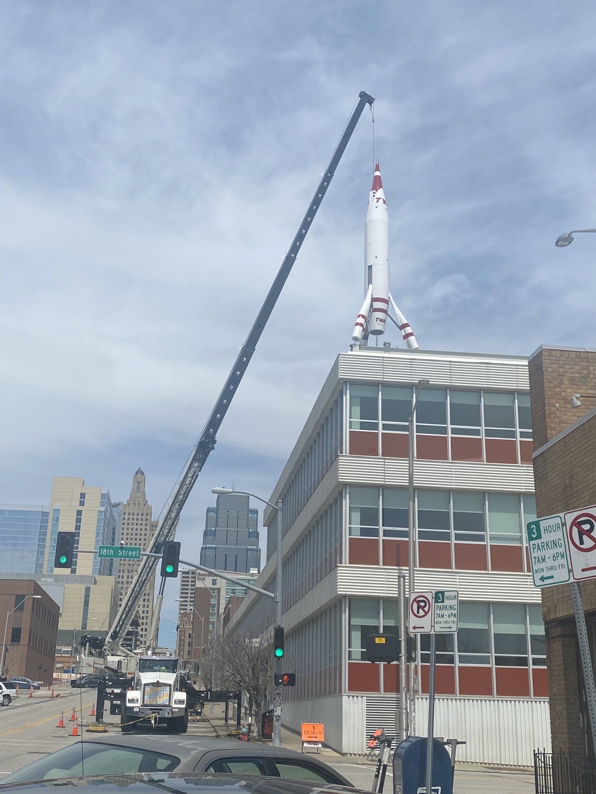 A crane is lifting a rocket on top of a building