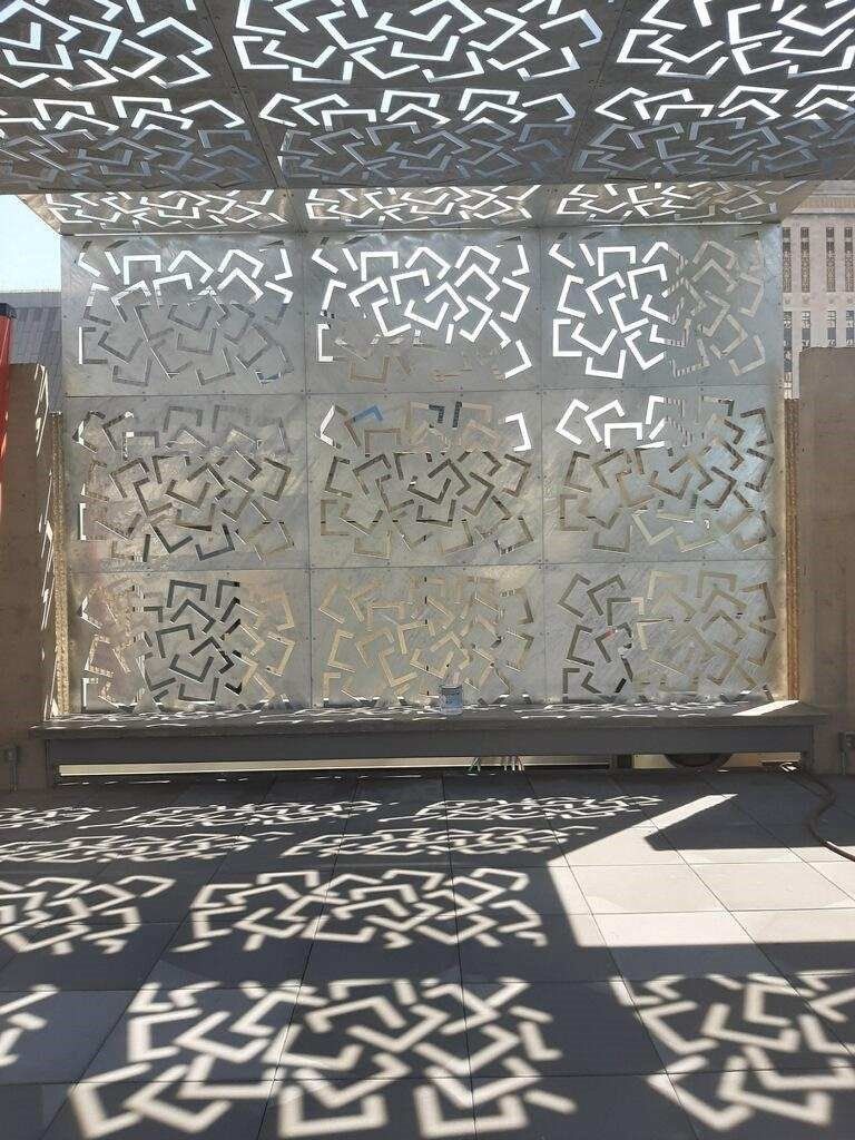 A wall with a pattern on it and a bench in front of it.
