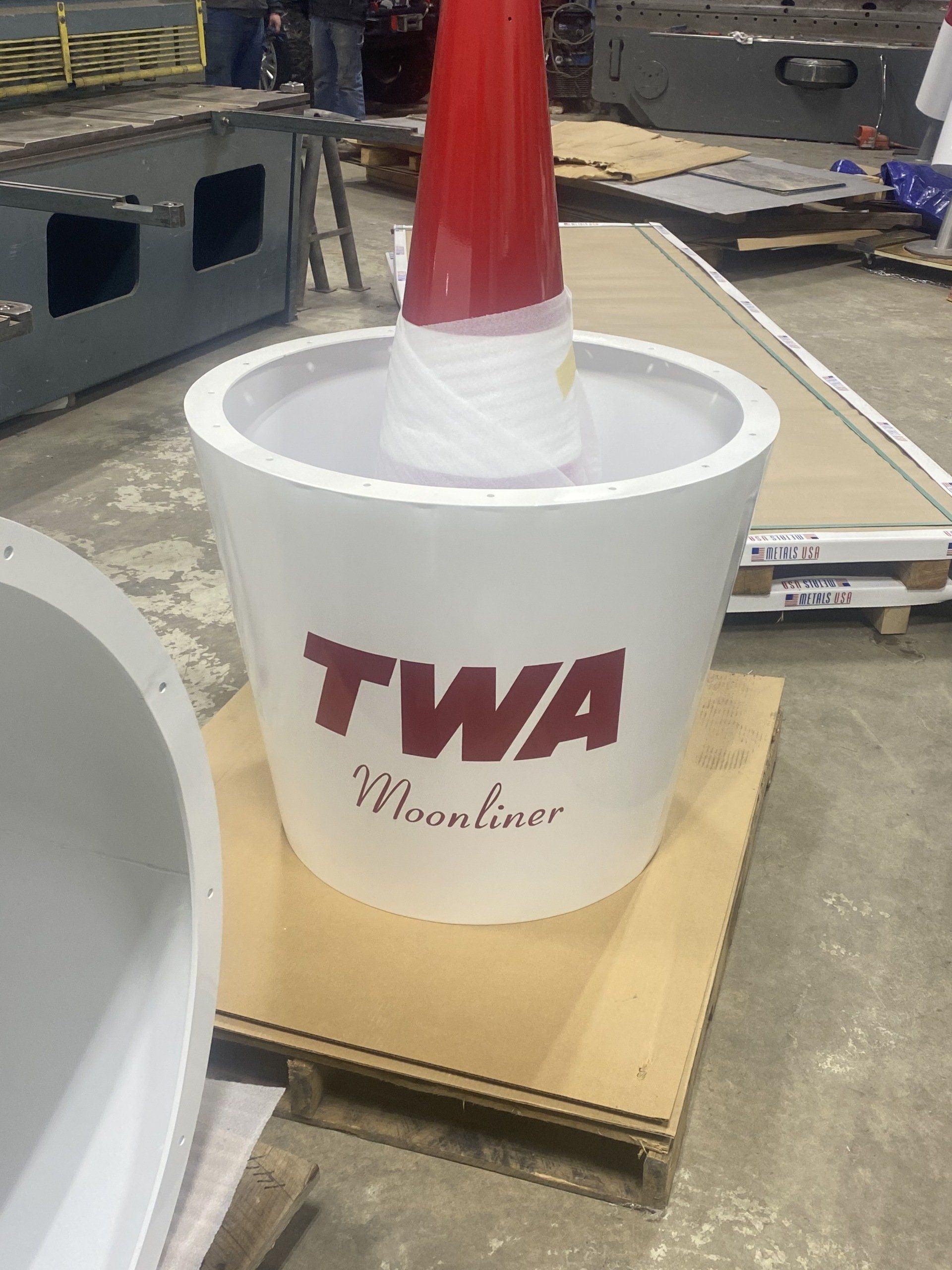 A white bucket with twa written on it is sitting on a wooden pallet.
