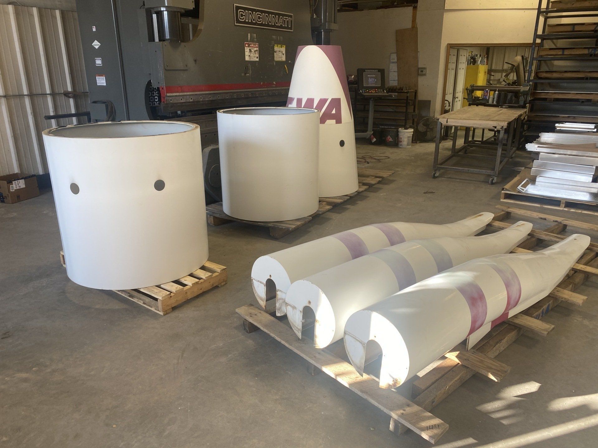 A bunch of white cylinders are sitting on wooden pallets in a room.