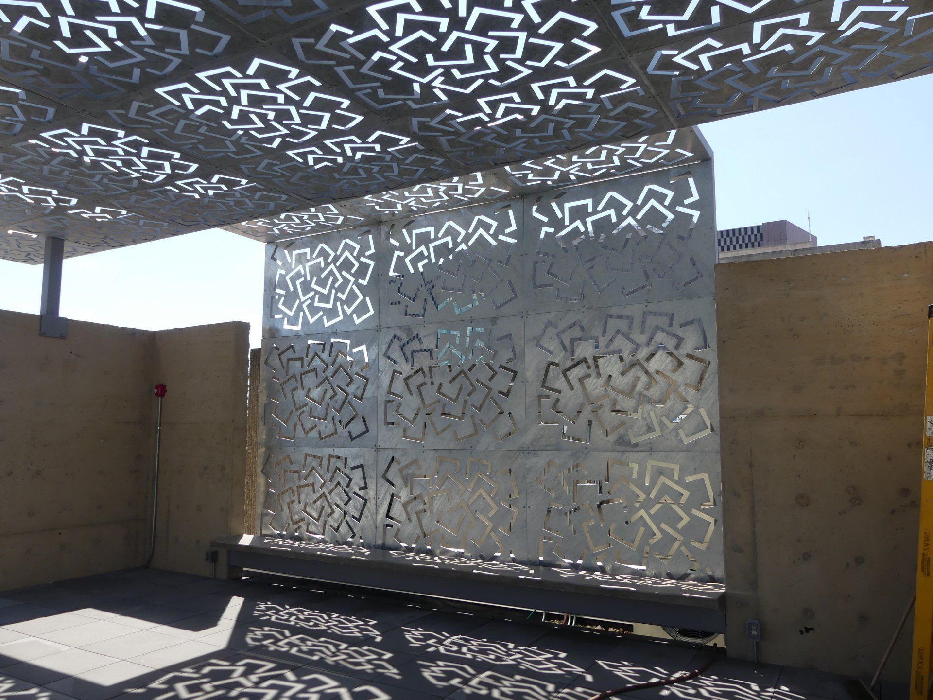 A metal wall with a pattern on it is sitting under a canopy.