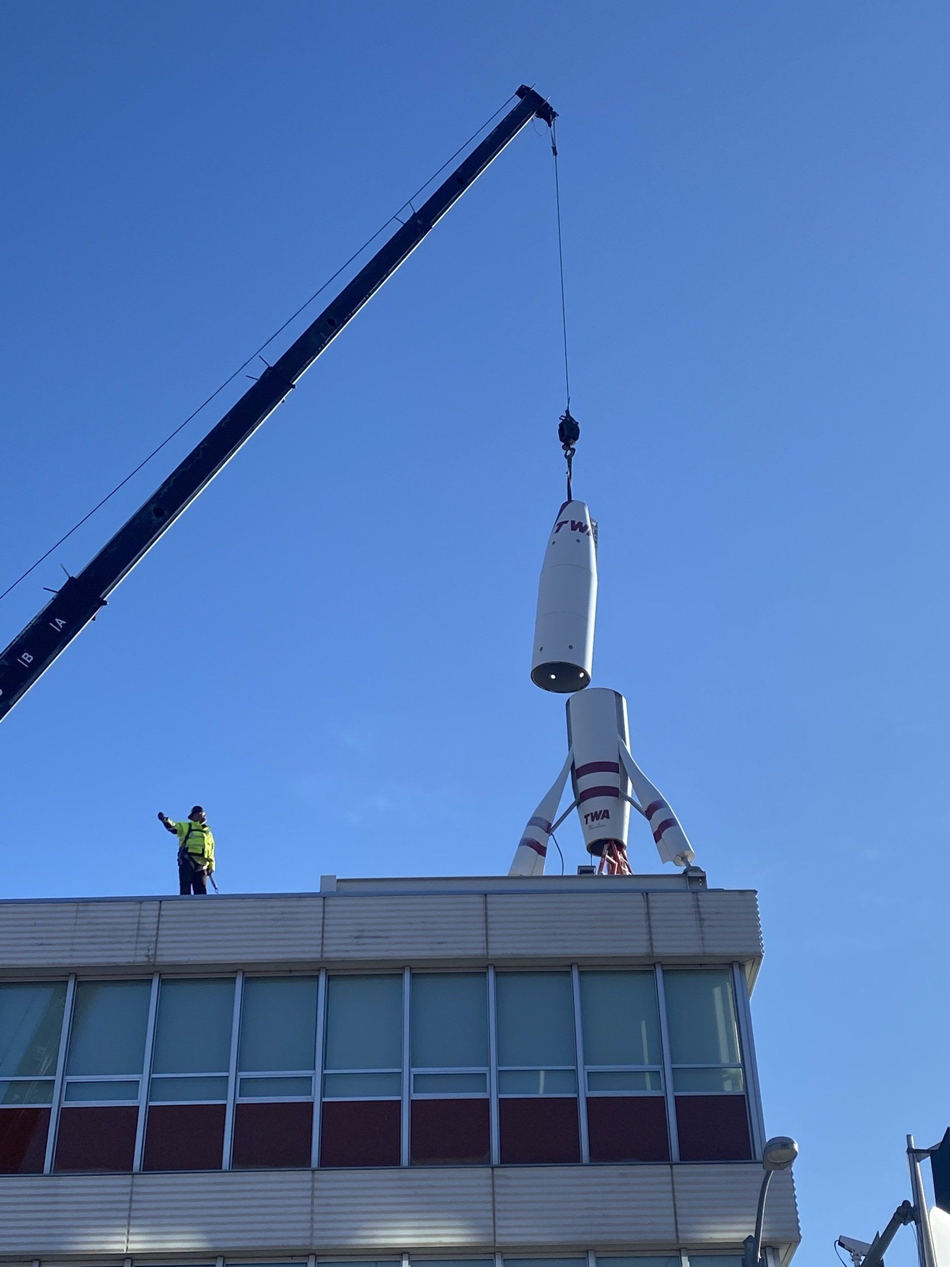 A crane is lifting a large object on top of a building